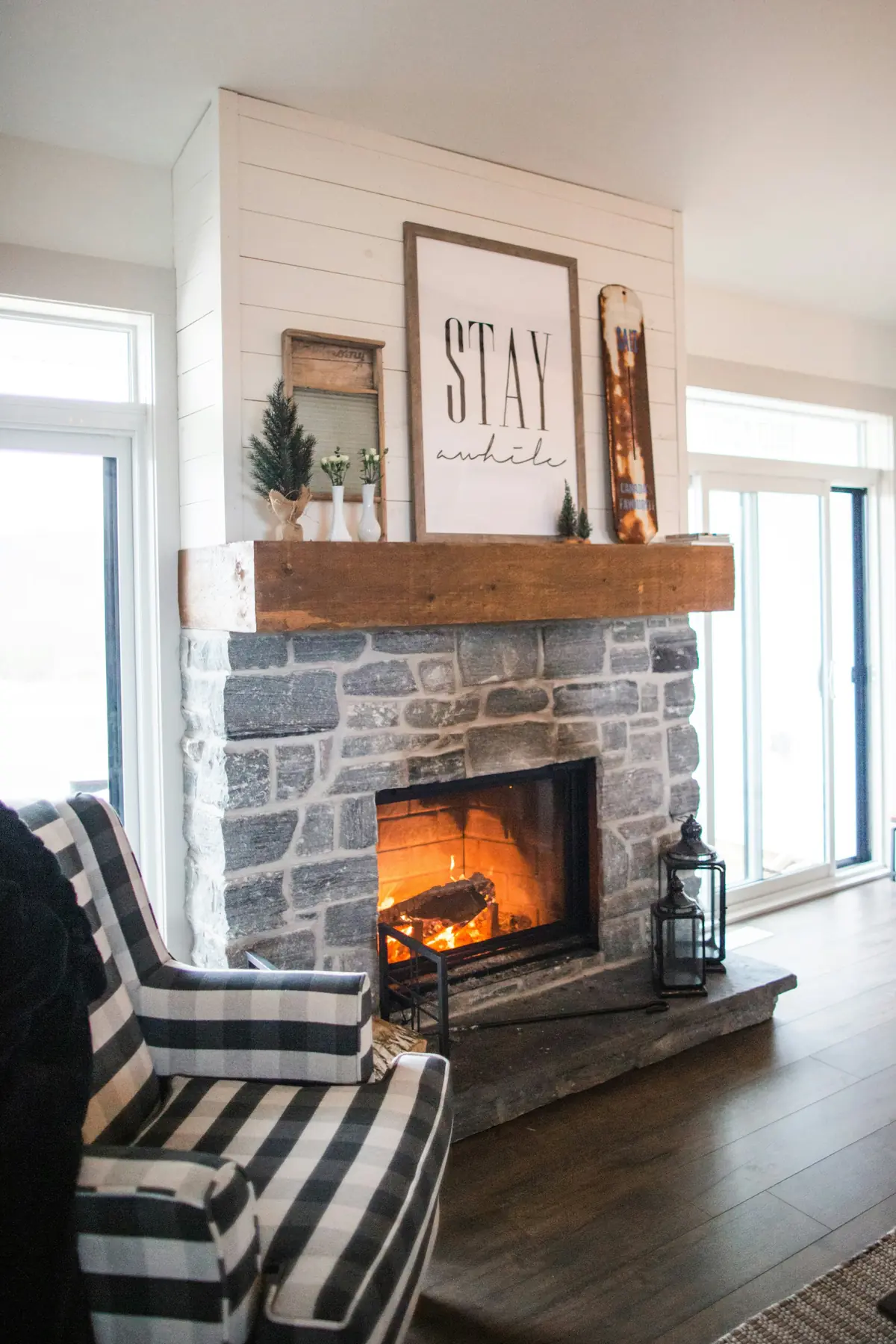 A stone fireplace with a fire going in a bright living room